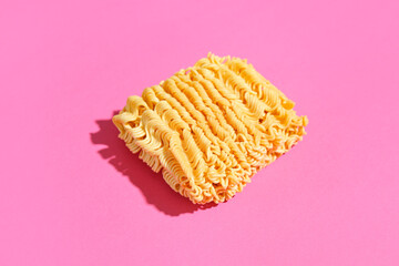 Raw instant noodles on pink background