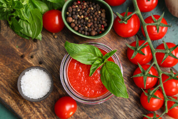 Jar of tomato sauce with basil and peppercorn on green background