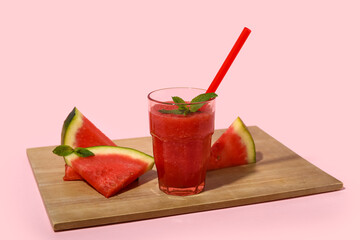 Glass of fresh watermelon juice with mint on pink background