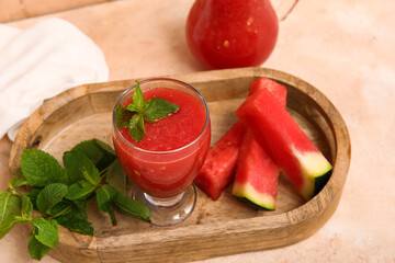 Glass of fresh watermelon juice with mint on beige background