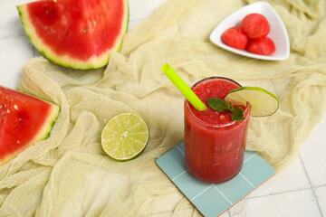 Glass of fresh watermelon juice with lime and mint on white tile table