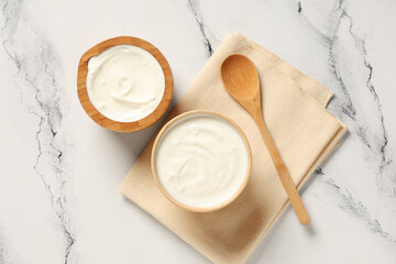 Wooden bowls of tasty yogurt on white background