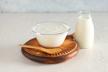 Glass bowl and bottle of tasty yogurt on white background