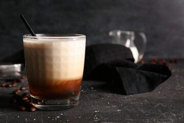 Glass of White Russian cocktail and coffee beans on black background