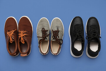Different stylish male shoes on blue background