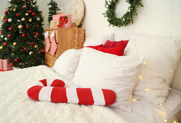 Bed with candy cane pillow and Christmas lights in bedroom