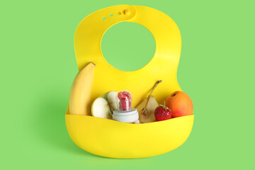 Bib with baby nibbler and fruits on color background