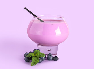 Glass of fresh blueberry smoothie with mint and berries on lilac background