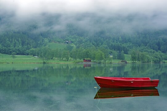 A small, red boat on a calm lake, idyll, surrounded by fog and green nature, Stryn, Mindesundet, Fjordland, Norway, Europe