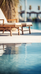 Two empty lounge chairs sit by the edge of a clear blue pool. The surface of the water reflects the sunlight, creating a shimmering effect, blurred background, copy space