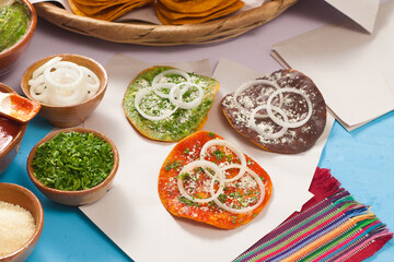 Group of 3 toasts on white paper and clay containers containing powdered cheese and chopped parsley.