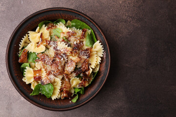 Tasty pasta with bacon and basil on brown table, top view. Space for text
