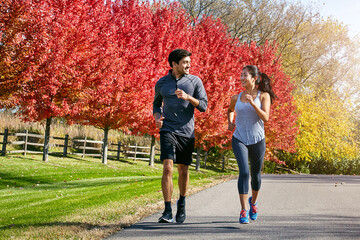 Couple, running and fitness with cardio, challenge and energy with exercise, wellness and bonding together. Healthy people, outdoor and man with woman, runner or speed with smile, training or support