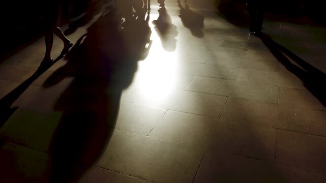 Capturing the shadows of people walking on the street illuminated by artistic light