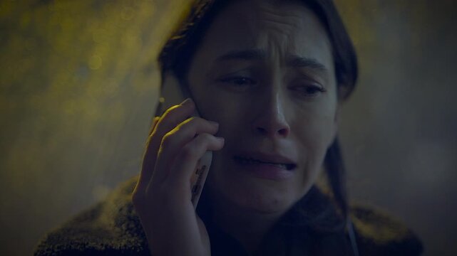 A distressed woman is depicted on a phone call, showcasing an emotional moment in a dark scene