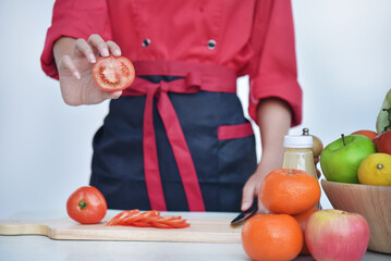 Close up Females Chef hands holding chop Wooden cutting board home kitchen. Women Chef hand cutting slice red tomato prepare fruit vegetables. Crop Woman hands use knife chopping organic tomato