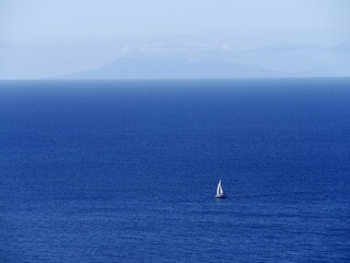 Isolated catamaran sailing ship in blue caribbean sea and island in the background in lesser antilles