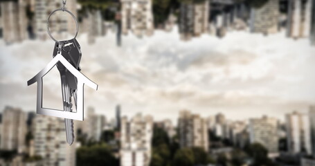 Image of silver house key over cityscape