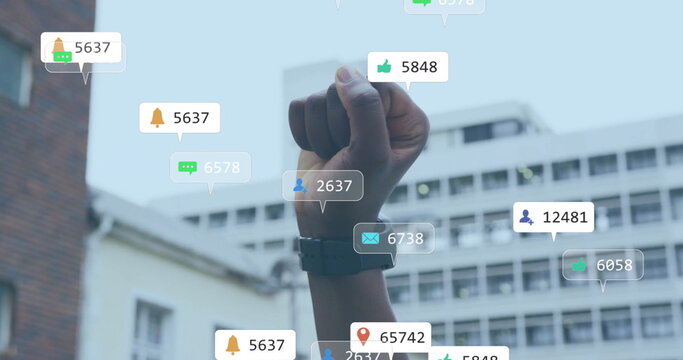 Image of social media notifications over african american woman raising fist in city