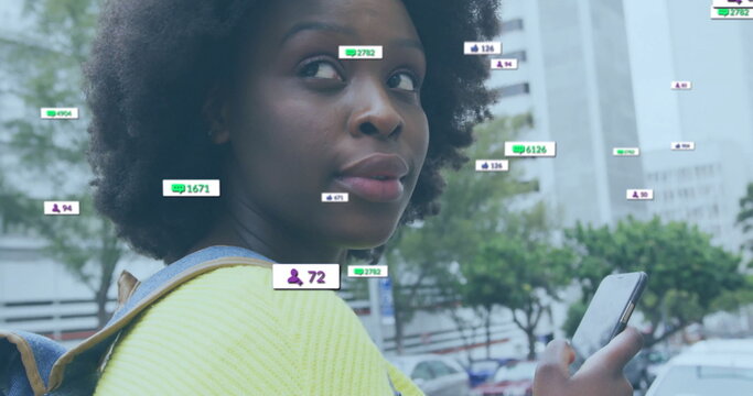 Image of media notifications over african american woman using smartphone in city street