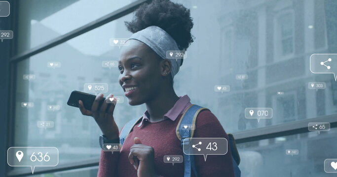 Image of media notifications over african american woman talking on smartphone in city