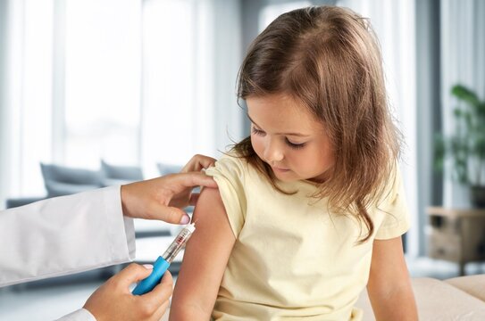 Pediatrician doctor injecting vaccine to child