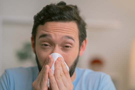 Sick man blowing his nose while suffering from cold