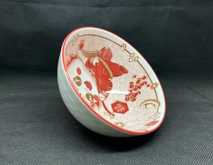 A bowl with unique Chinese carvings, with a black background behind it.