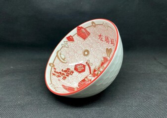 A bowl with unique Chinese carvings, with a black background behind it.