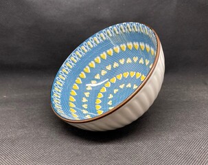 A bowl with unique heart themed carvings, with a black background behind it.