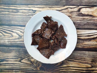 The deer jerky after cooking is served on a white plate “Dendeng Rusa” from Merauke, Papua, Indonesia, is a traditional Indonesian dish made from deer meat that is dried and seasoned.