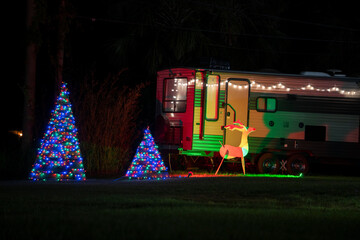 Camper van on front yard with brightly illuminated christmas decorations. Outside decor of caravan...