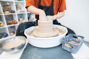 Close-up of a potter's hands working on a pottery wheel. 