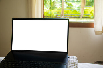 Computer or laptop. Morning time with warm light. Blank laptop screens on spring bed and window background. work from home concept. The photo is out of focus, blurred, and noisy.