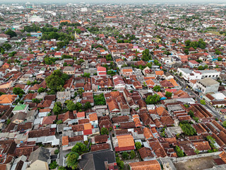 Aerial view of a densely populated urban area with a mix of traditional and modern buildings, lush trees, and a network of narrow streets.