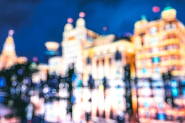 A blurred city skyline at night, illuminated by city lights, with a blue sky in the background.