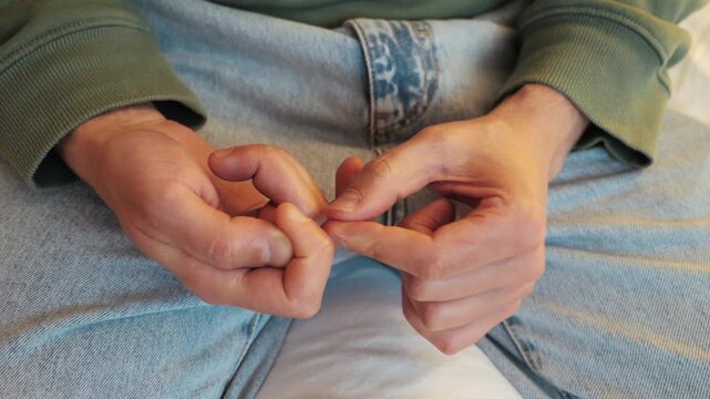 Person picking at nails nervously, close up on arms.