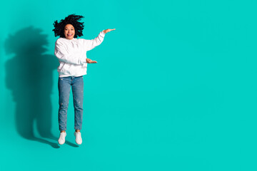 Photo of young huge chevelure hair lady wearing white hoodie jeans hold two arms size measurement isolated on aquamarine color background