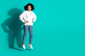 Photo portrait of young funny chevelure hairstyle lady jumping in white hoodie and stylish jeans isolated on aquamarine color background