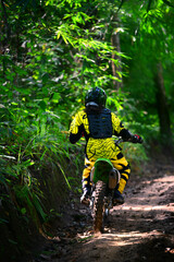 Motocross racing on the rough way in deep forrest.