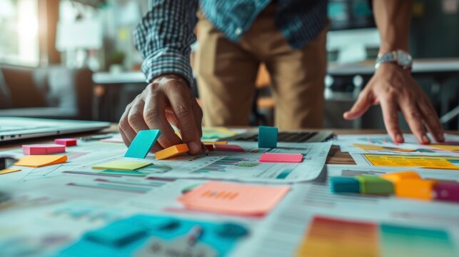 A person actively engaged in brainstorming and planning with colorful sticky notes on a workspace document.