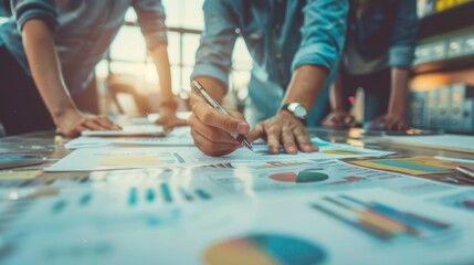 Obraz premium Close-up of hands analyzing charts and graphs in a collaborative workspace, highlighting teamwork and strategy in business.