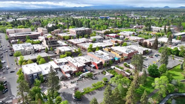 Aerial Arc Shot of Downtown Bend Oregon with Green Spaces and Mountain Backdrop