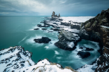 The beautiful Londrangar and Pofubjarg coastal cliffs in Iceland, basalt rock formations, Atlantic Ocean waves during winter storm