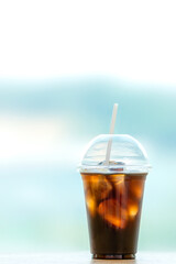 Iced Americano in a take-out plastic cup. Window with a panoramic view