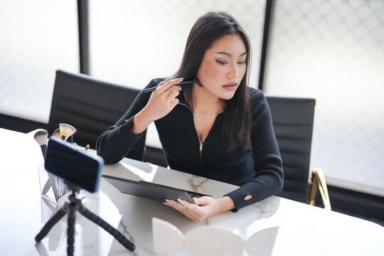 Asian girl makeup artist Professional Woman blogger vlogger is showing cosmetics products with recording video Beauty influencer asian girl video online marketing.