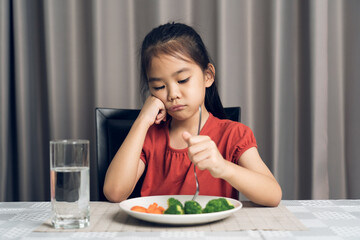 Little cute kid girl refusing to eat healthy vegetables. Children do not like to eat vegetables.