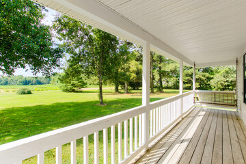 Wide Country Porch With White Railing And Wooden Floor Overlooking Green Landscape