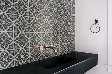 Modern Bathroom Sink With Black Countertop And Patterned Tile Backsplash