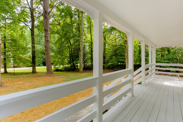 Fototapeta premium Cozy Porch With White Railings Overlooking A Green, Wooded Landscape